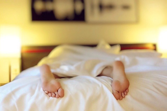 nohy, koukající z postele